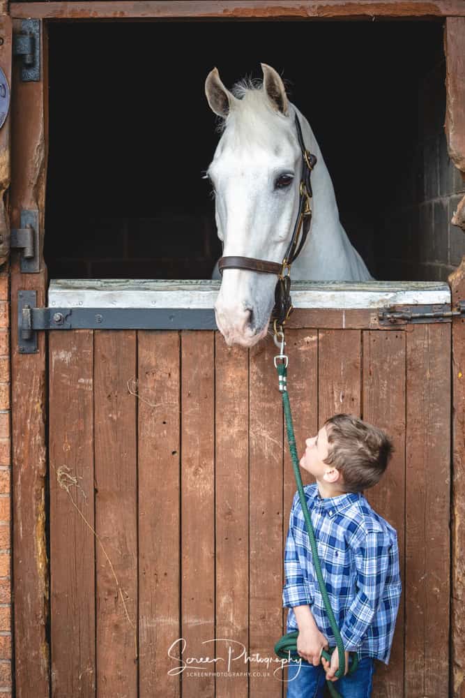 Equine portrait photography nottingham boy with horse at stable door looking